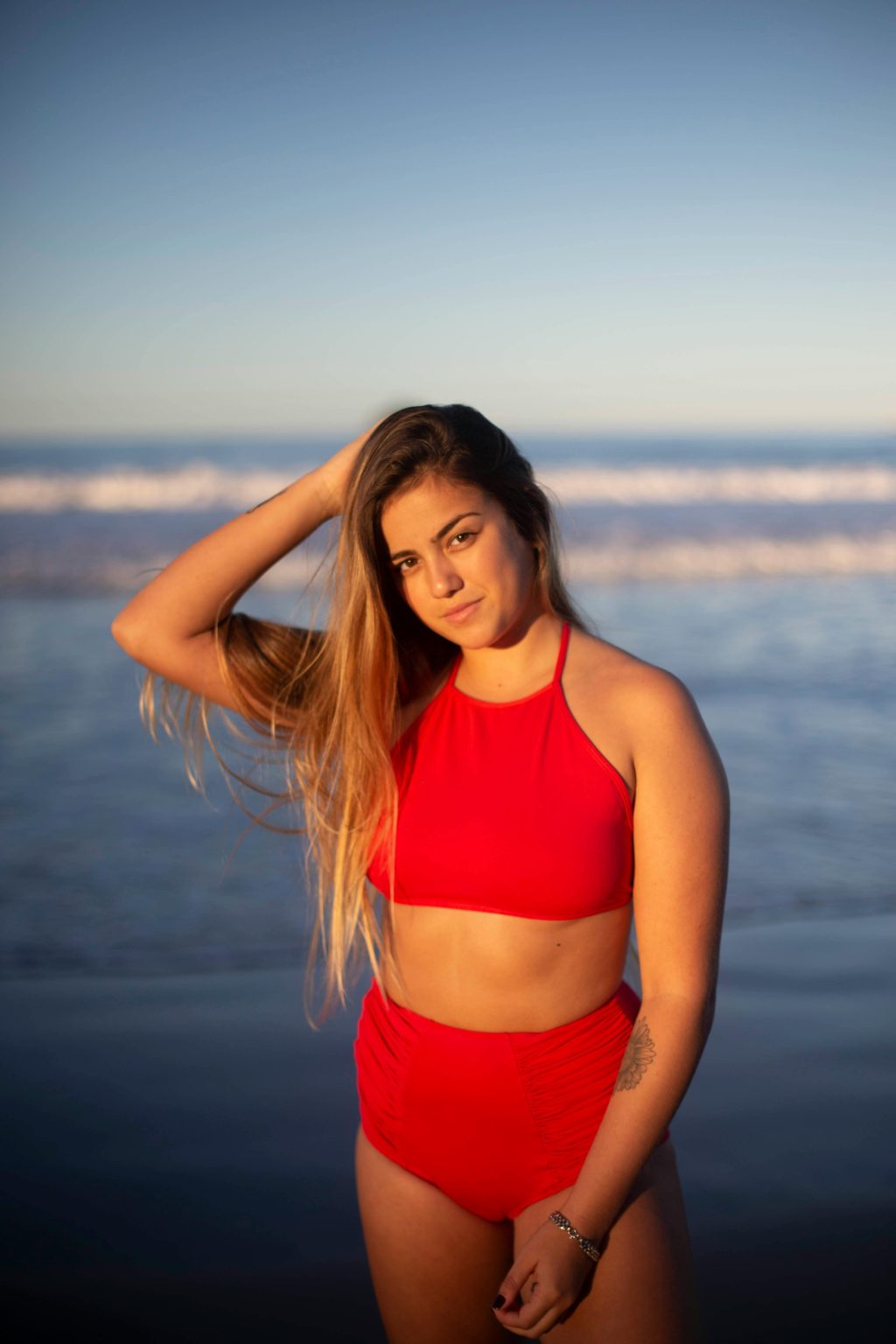 Vrouw draagt high waist bikini in retro-stijl op het strand, demonstreert de flatterende pasvorm en volle bedekking.
